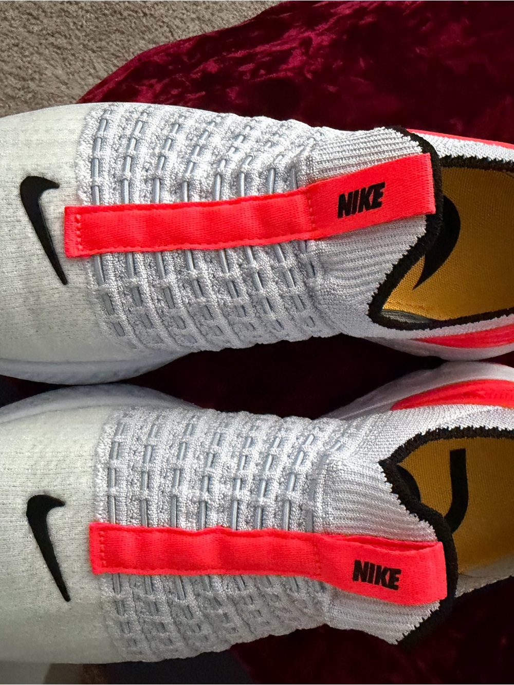 Nike White Flyknit Slip-On Sneakers with Neon Coral Pull Tabs